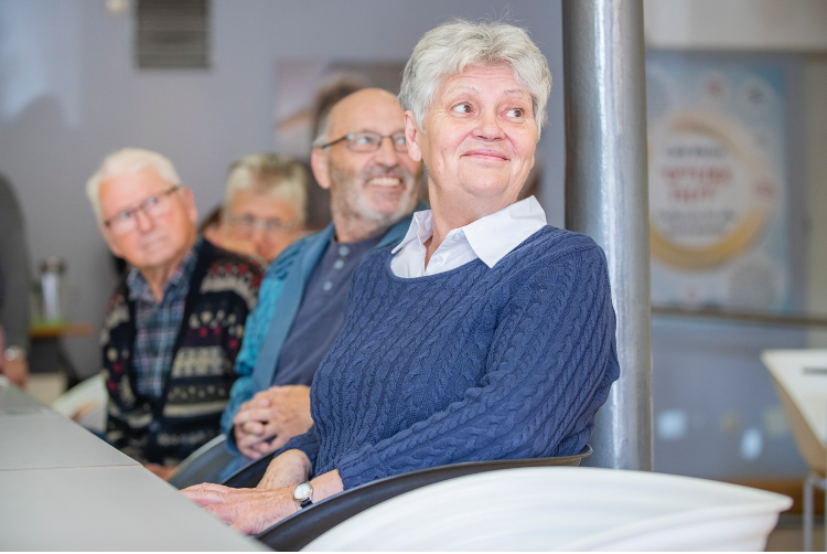 Seniorinnen und Senioren sitzen lächelnd an einem Tisch