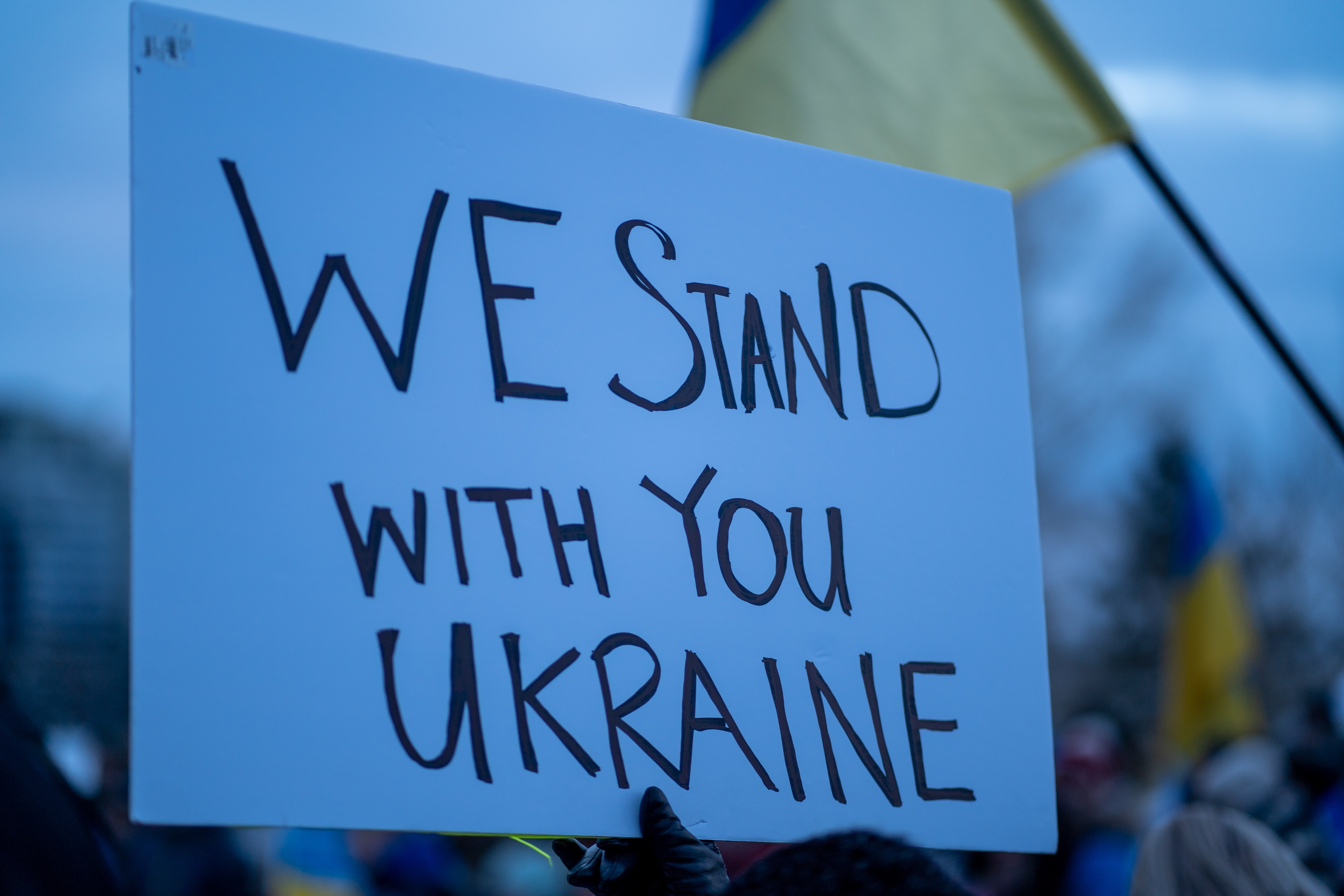 Pappschild mit der Aufschrift "We stand with you Ukraine"