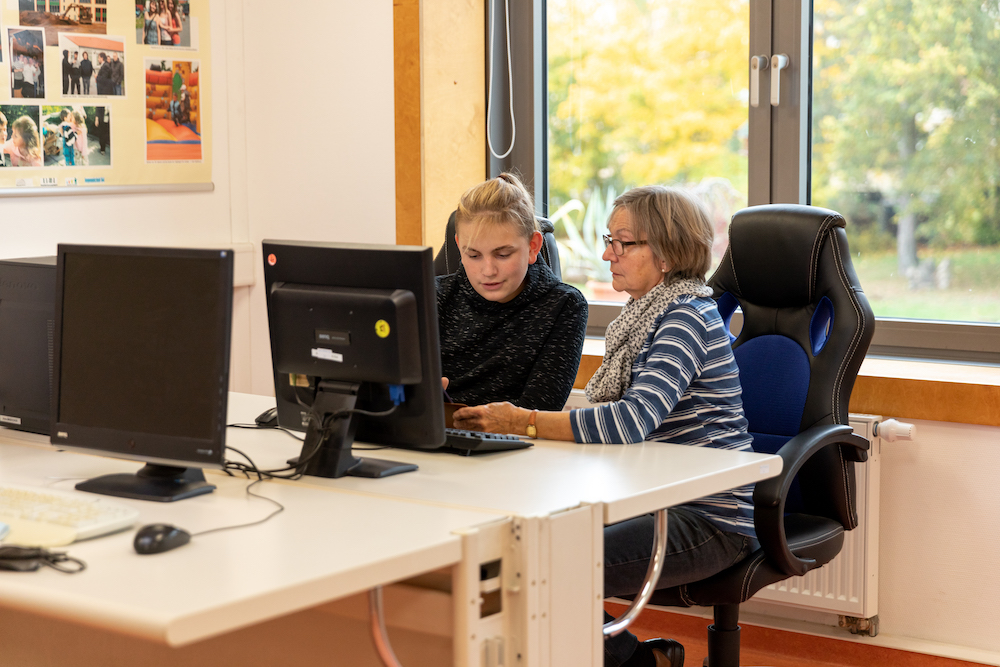 Eine ältere Frau und ein Teenager sitzen am Computer-Bildschirm