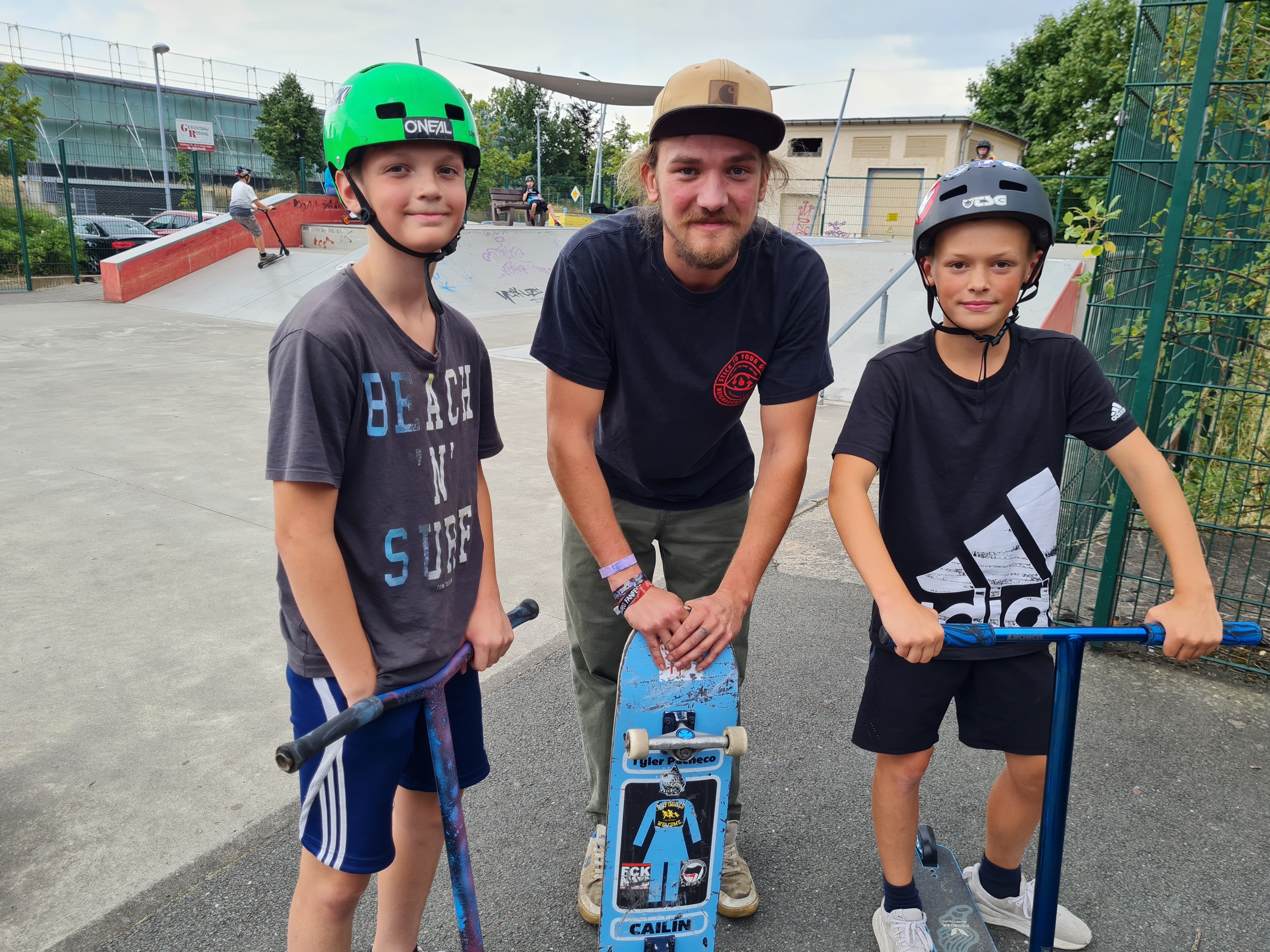 (c) MGH Zwönitz Drei Jungs tragen Helme, stehen auf ihren Rollern und lächeln.