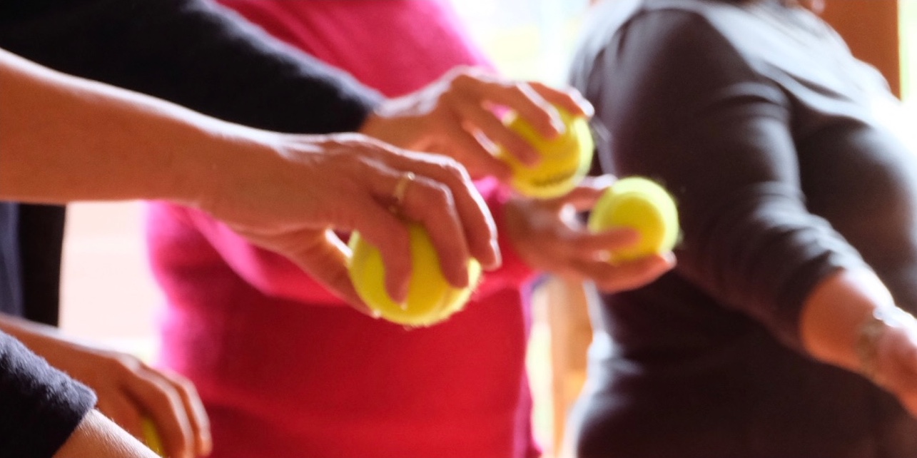 Ausgestreckte Hände halten Tennisbälle