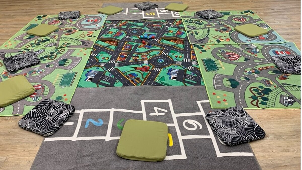 Mehrere Spieleteppiche mit aufgemalten Straßen liegen nebeneinander