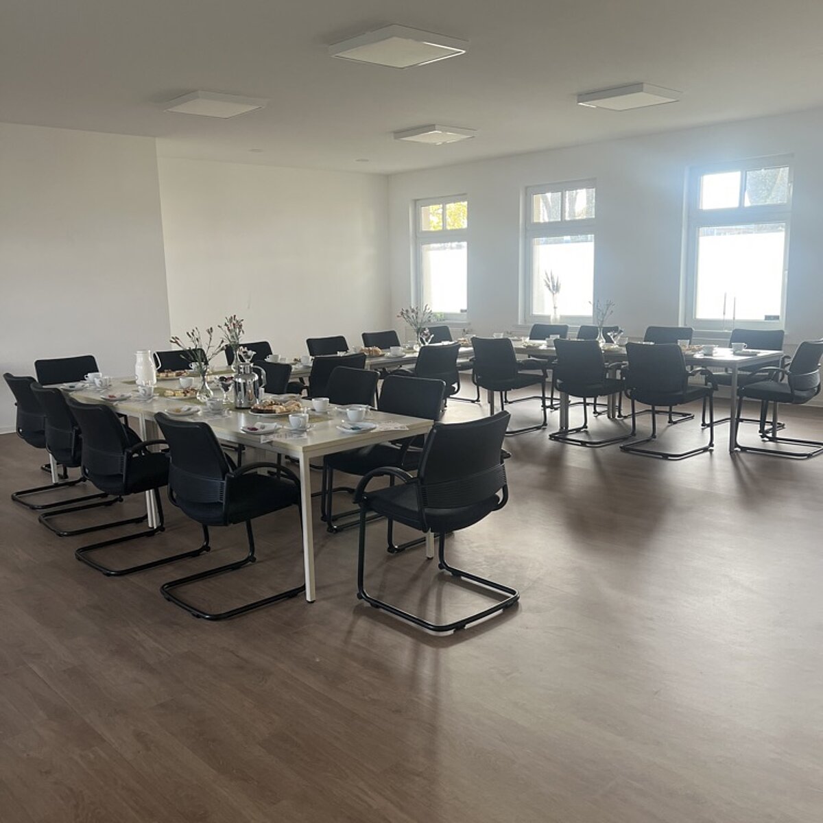 Großer Saal mit eingedeckter Kaffeetafel.