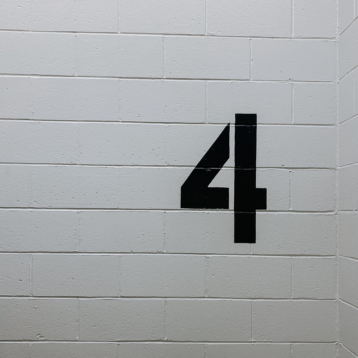 Eine schwarze Vier, die auf eine graue Wand gemalt wurde.