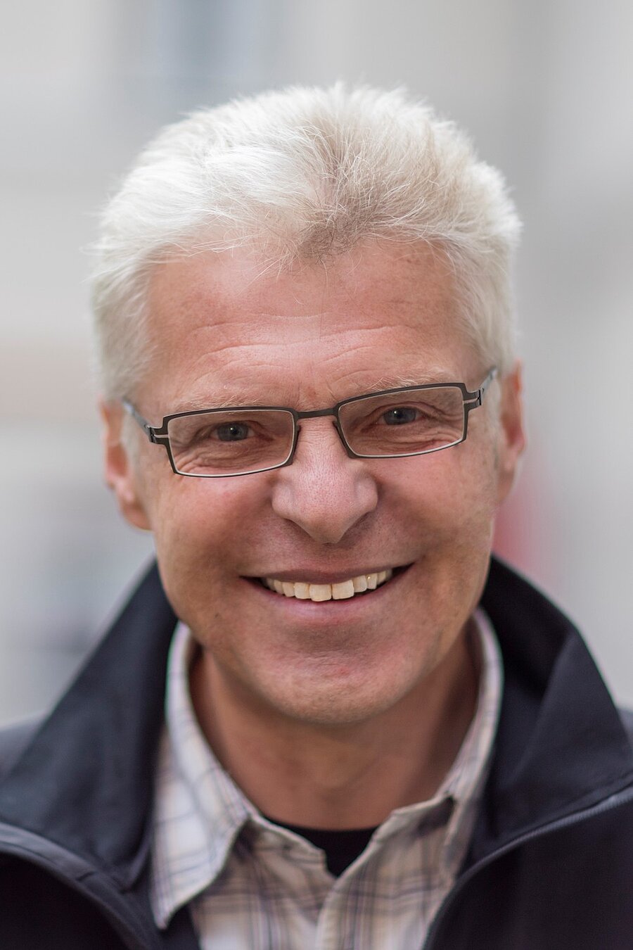 Porträt von Dr. Hermann Scheuerer-Englisch mit grauen Haaren, Brille und blauer Jacke