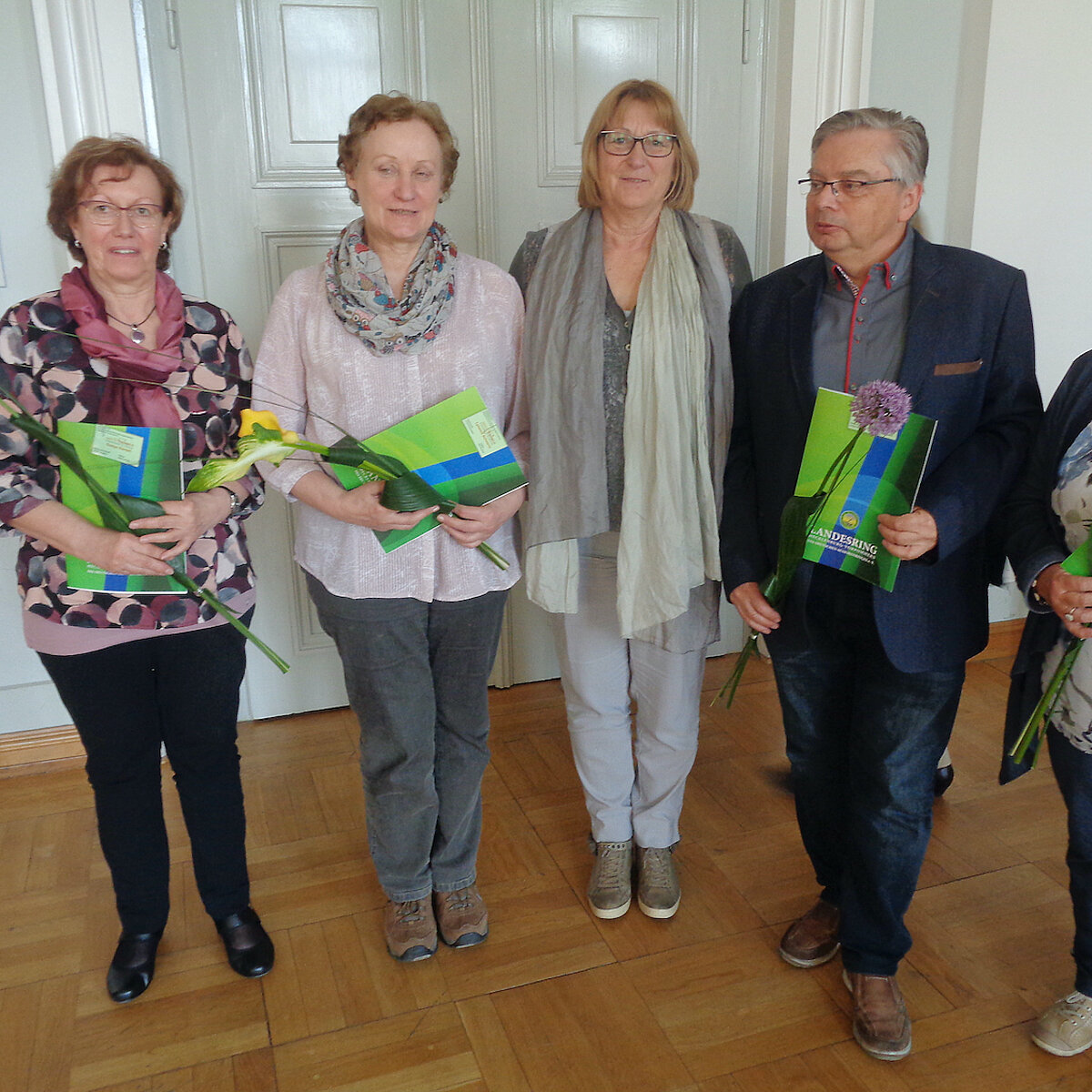 Vier Seniorinnen und ein Senior stehen nebeneinander und halten ein Zertifikat in der Hand.