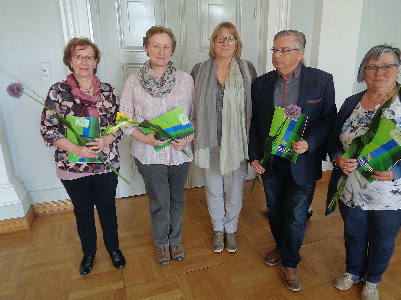 Vier Seniorinnen und ein Senior stehen nebeneinander und halten ein Zertifikat in der Hand.