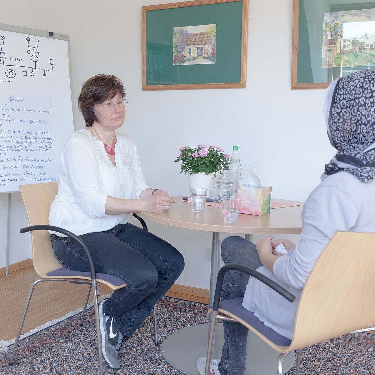 Zwei Frauen sitzen an einem runden Tisch im Gespräch
