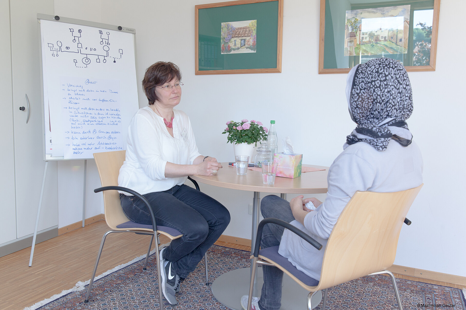 Zwei Frauen sitzen an einem runden Tisch im Gespräch