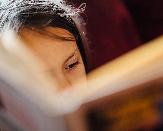 Mädchen liest konzentriert in einem Buch.