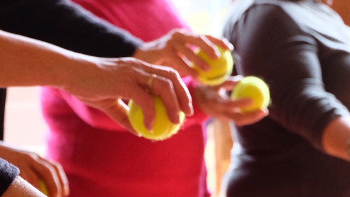 Ausgestreckte Hände halten Tennisbälle