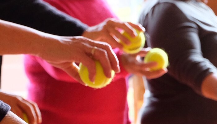 Ausgestreckte Hände halten Tennisbälle