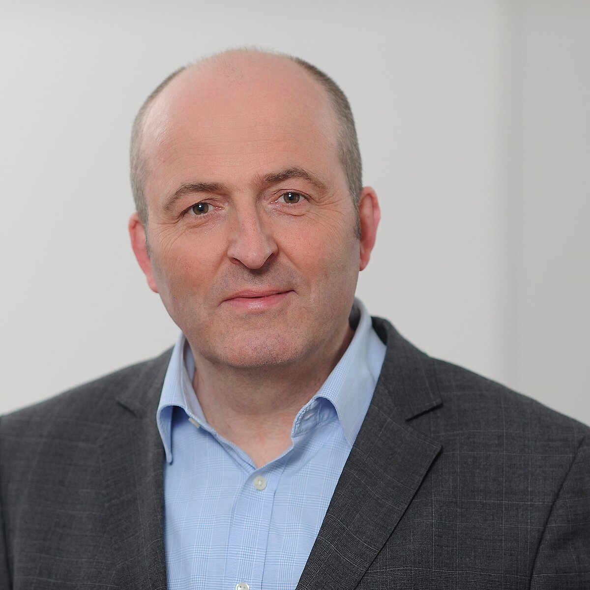 Porträtbild von Prof. Dr. Berthold Vogel, er trägt ein blaues Hemd und ein dunkles Sakko