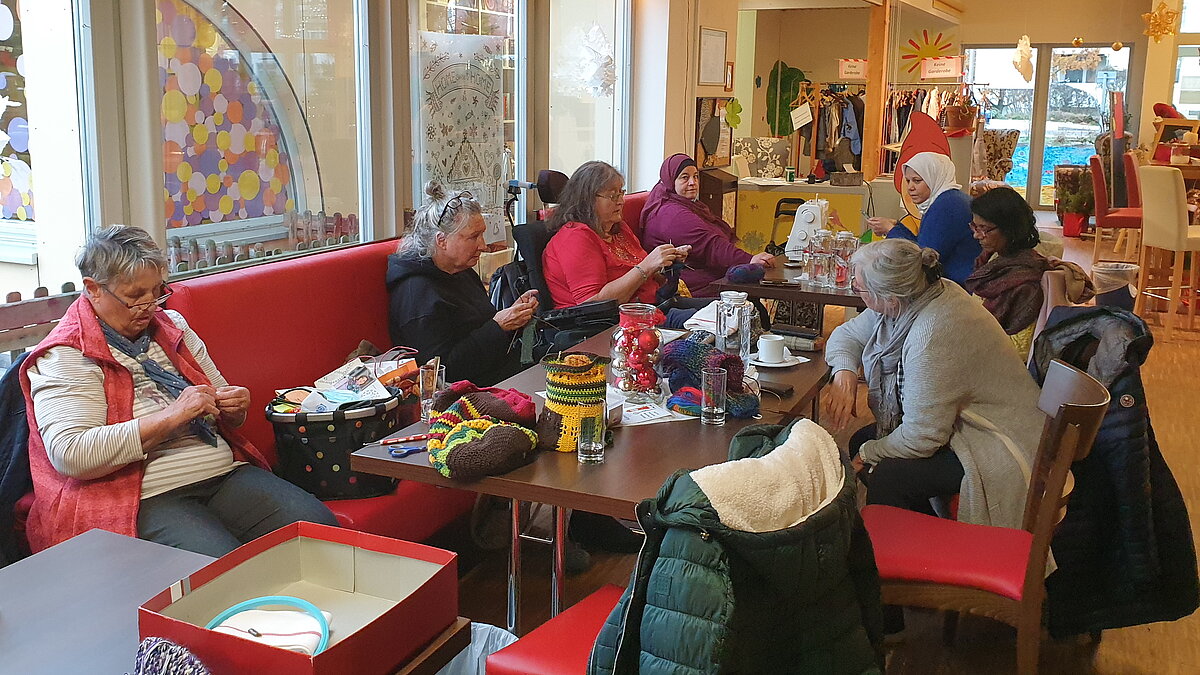 Vielen Frauen sitzen an einem großen Tisch und nähen.