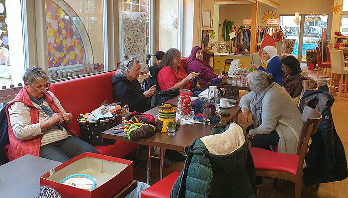 Vielen Frauen sitzen an einem großen Tisch und nähen.