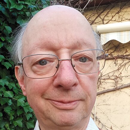 Ein Mann mit Brille lächelt in die Kamera. 