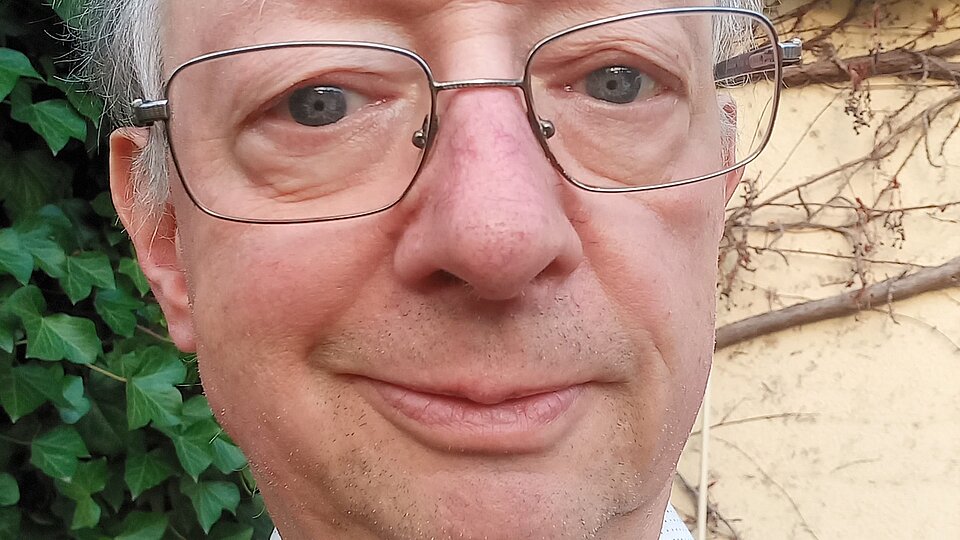 Ein Mann mit Brille lächelt in die Kamera. 