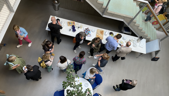 Viele Menschen stehen in einem Foyer und unterhalten sich in verschiedenen Gruppen