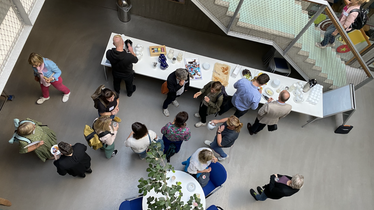 Viele Menschen stehen in einem Foyer und unterhalten sich in verschiedenen Gruppen