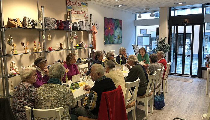 Dreizehn Seniorinnen und Senioren sitzen gemeinsam an einem langen Tisch
