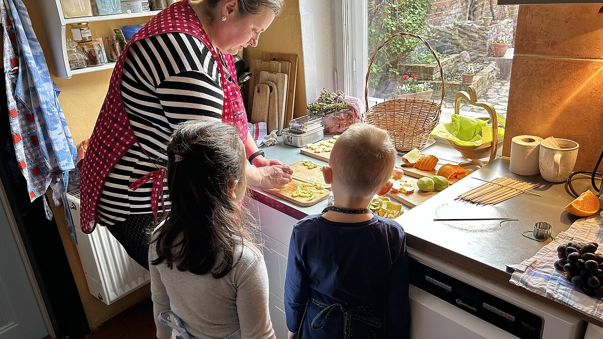 Eine Frau und zwei Kinder bereiten Essen zu