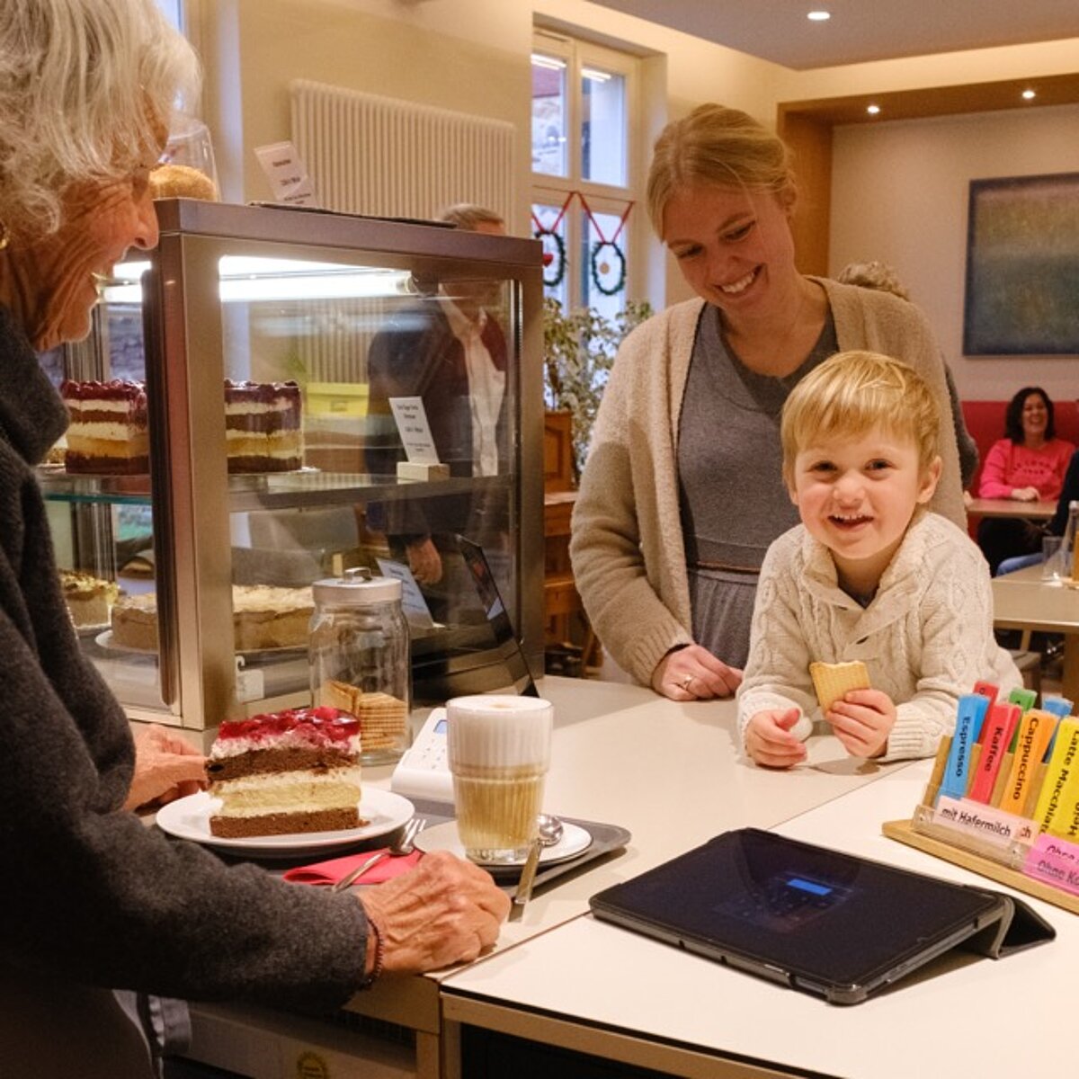 Kind und seine Mutter bekommen ein Stück Kuchen und Getränk an der Theke