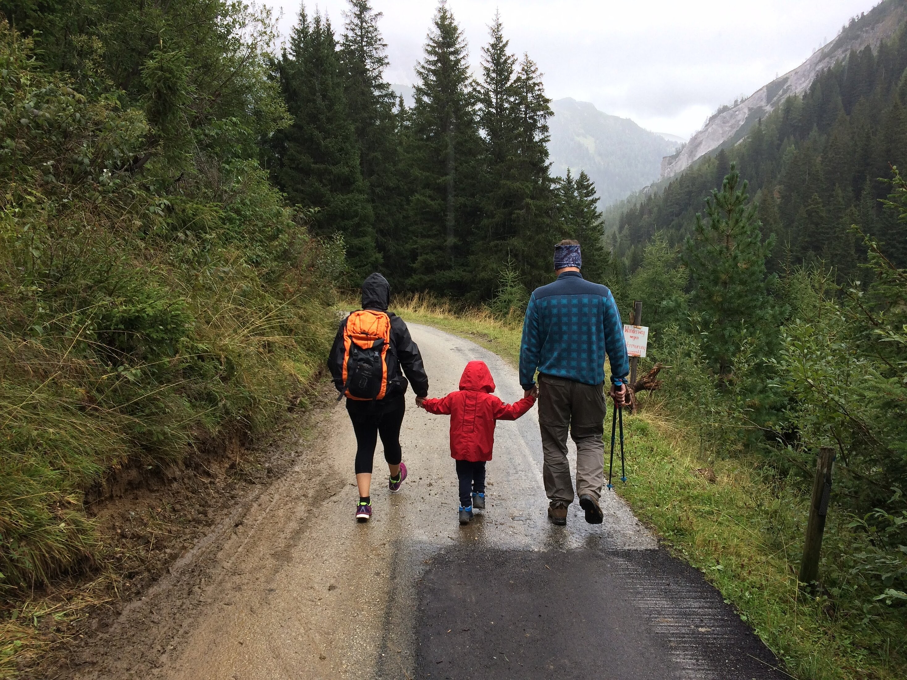 Mutter und Vater, die ein Kind in ihrer Mitte haben und wandern.