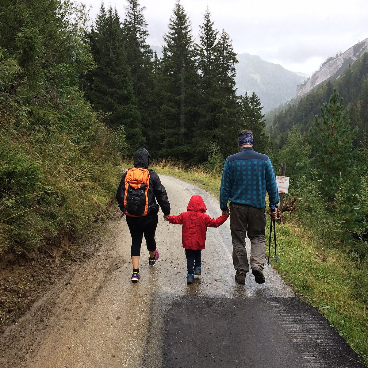 Mutter und Vater, die ein Kind in ihrer Mitte haben und wandern.