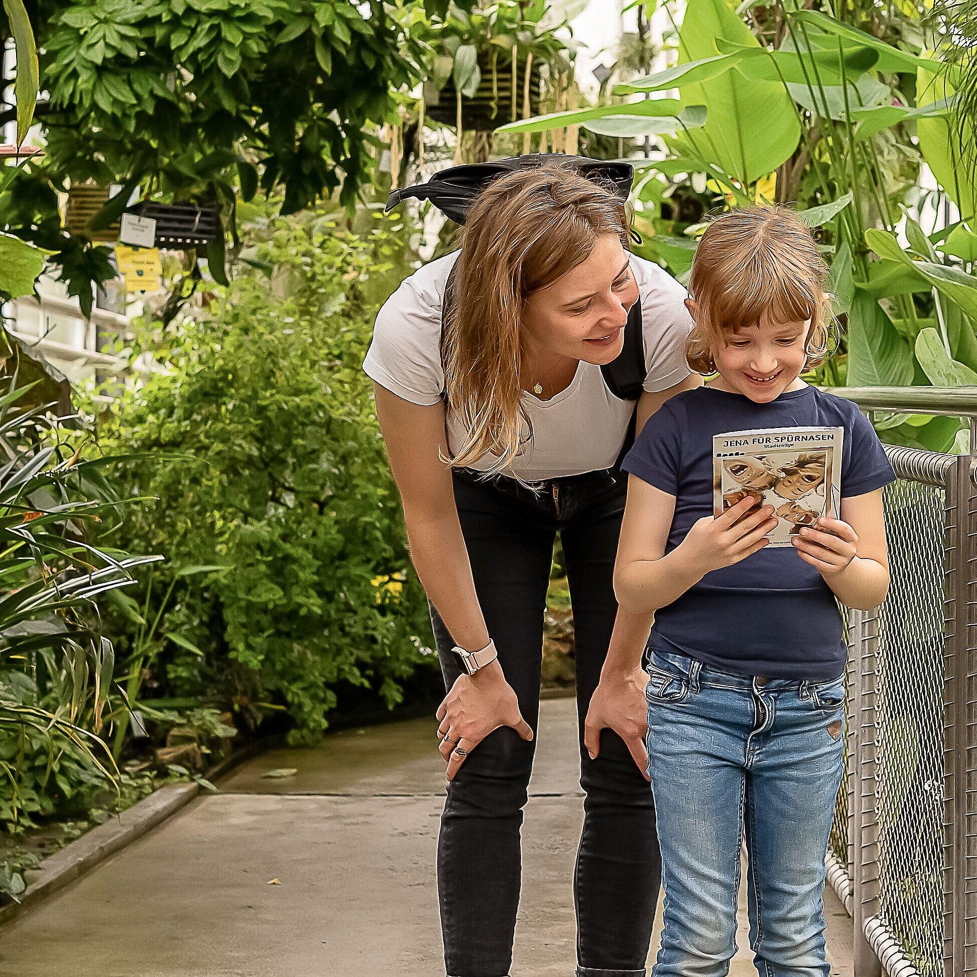 Ein Kind und eine Frau stehen zusammen in einem großen Tropenhaus eines Botanischen Gartens.