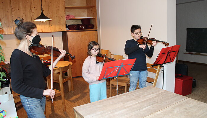 Eine Frau, ein Mädchen und ein Junge spielen Geige