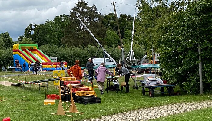 Auf einer Wiese stehen ein Trampolin, eine aufblasbare Rutsche und weitere Spielutensilien.