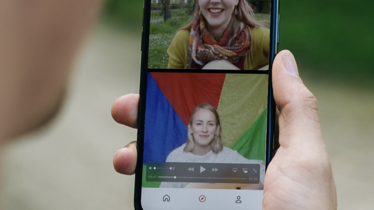 Hand hält Handy, auf dem der Live-Stream der Mehrgenerationenhäuser Fallbach und Casa zu sehen ist