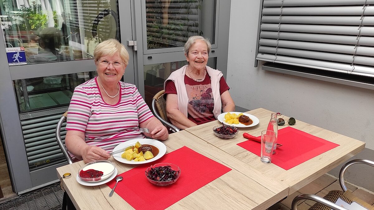 wei Seniorinnen sitzen am gedeckten Mittagstisch