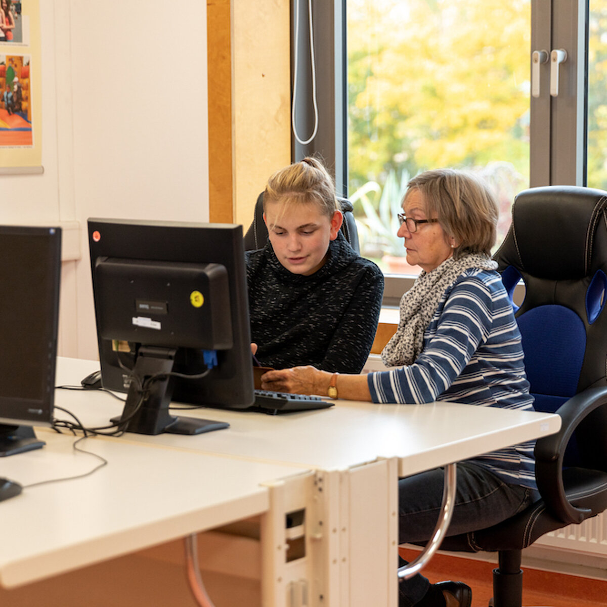 Eine ältere Frau und ein Teenager sitzen am Computer-Bildschirm
