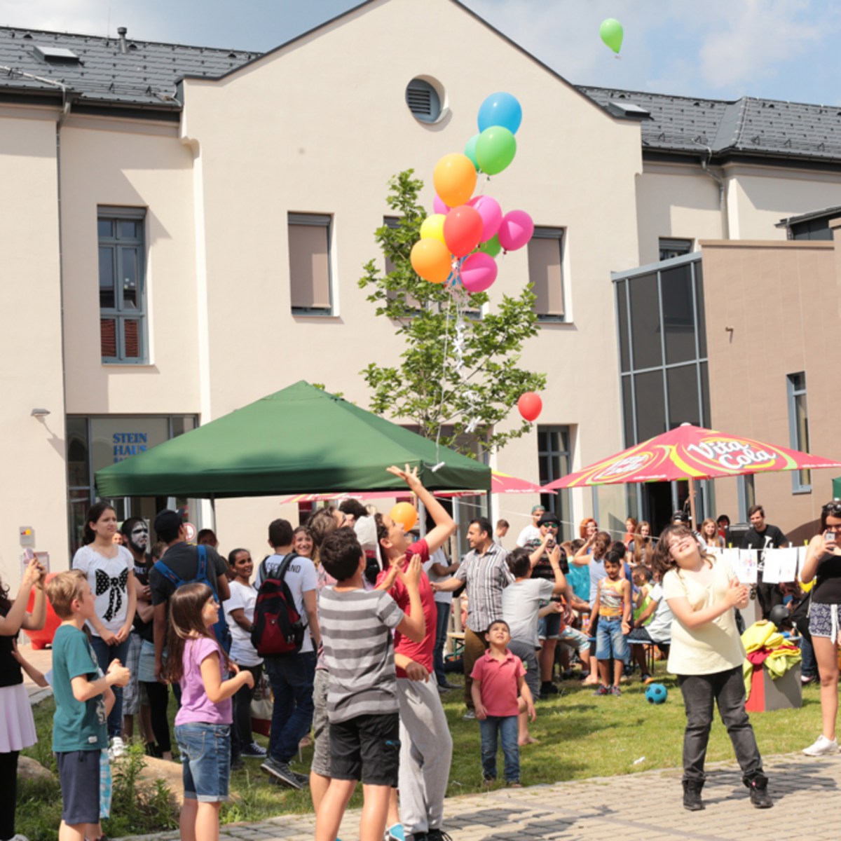 viele glückliche Menschen vor dem Steinhaus-Gebäude