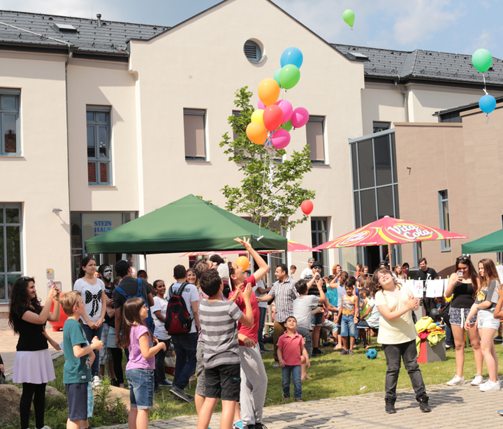 viele glückliche Menschen vor dem Steinhaus-Gebäude