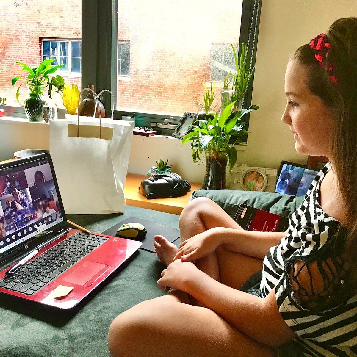 Mädchen sitzt vor Laptop, auf dem eine Videokonferenz läuft