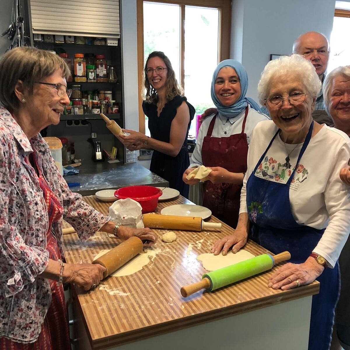 Nachbarschaftshilfe Taufkirchen Unterhaching eV Gruppe von Menschen verschiedenen Alters, die in einer Küche stehen und gemeinsam backen.