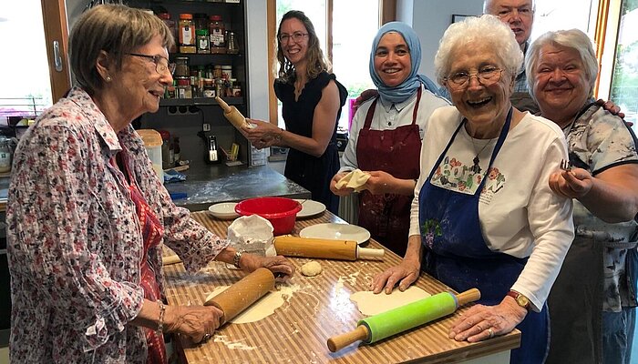 Nachbarschaftshilfe Taufkirchen Unterhaching eV Gruppe von Menschen verschiedenen Alters, die in einer Küche stehen und gemeinsam backen.