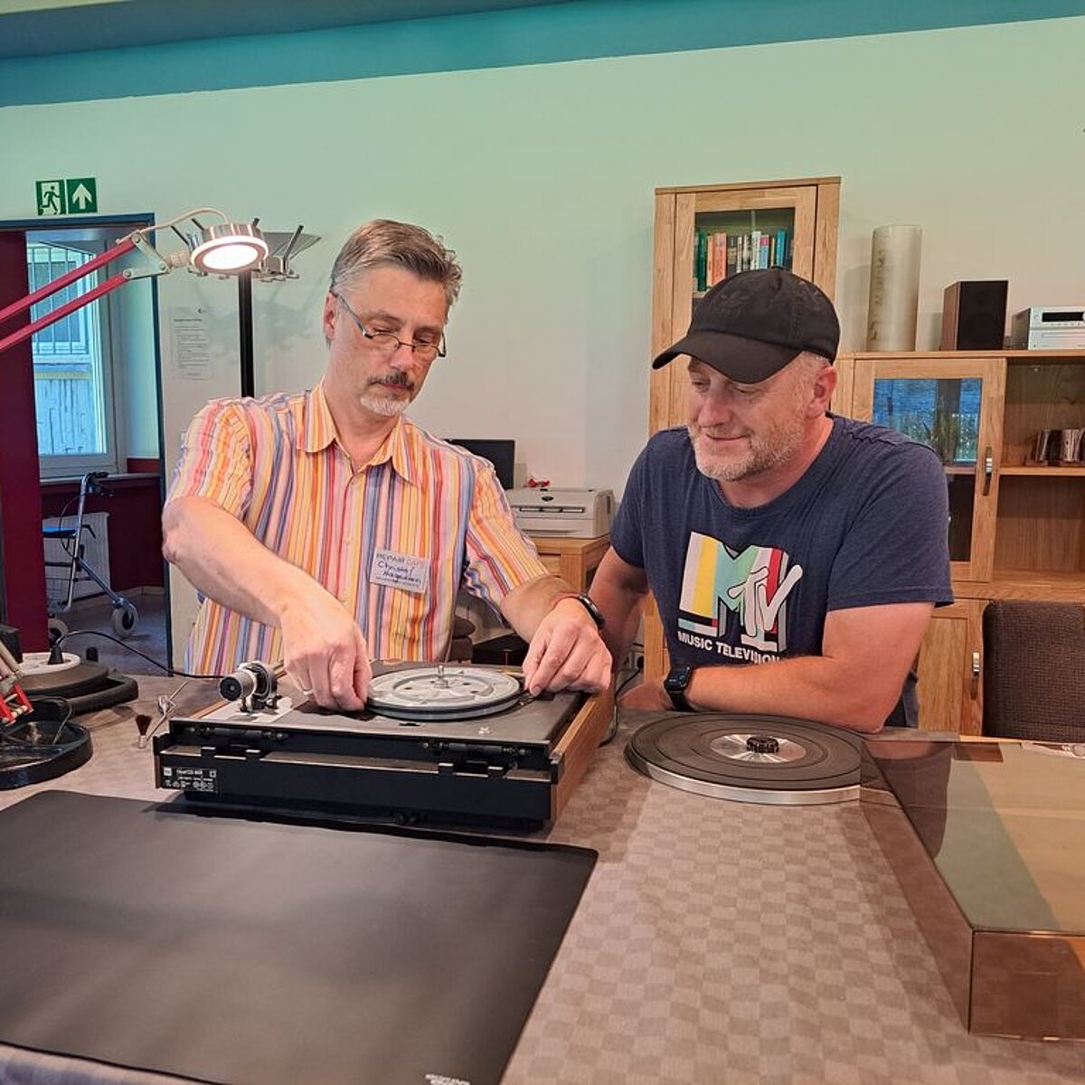 Zwei Männer reparieren einen Plattenspieler