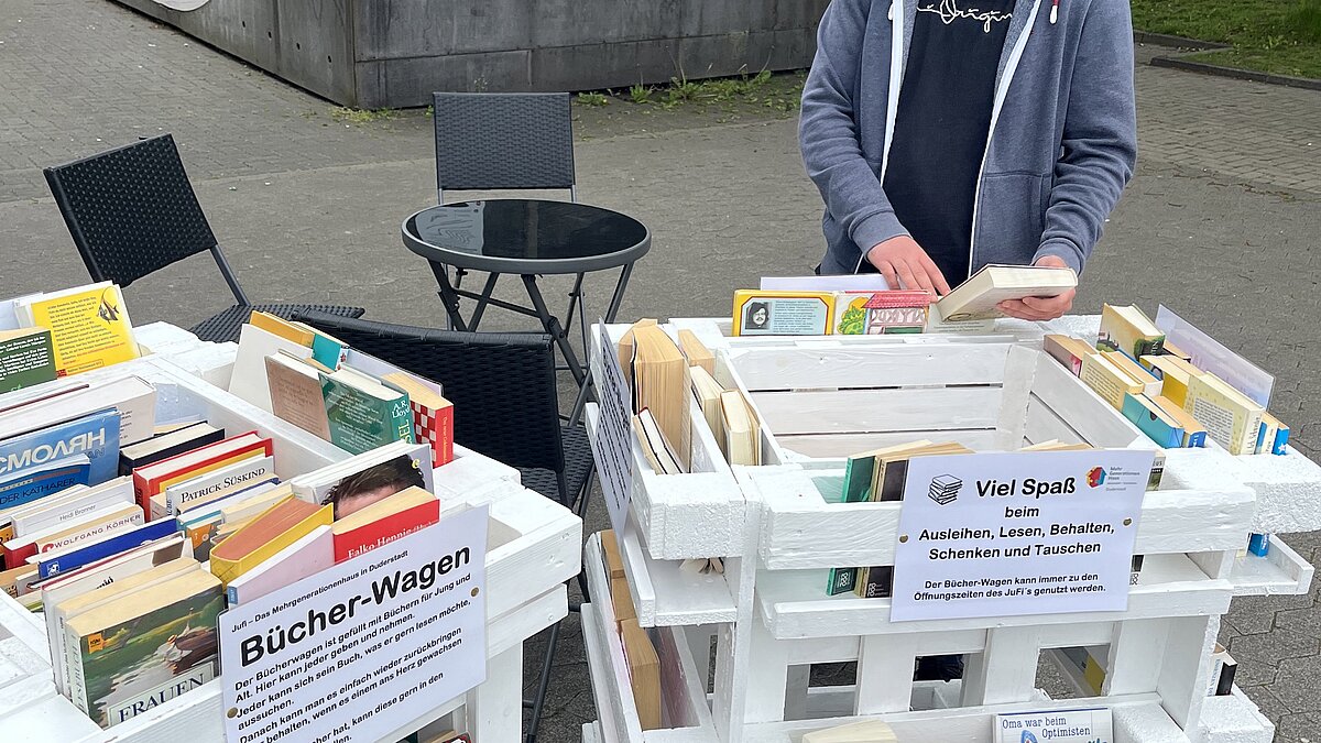 Ein Jugendlicher stöbert im rollenden Bücherwagen.