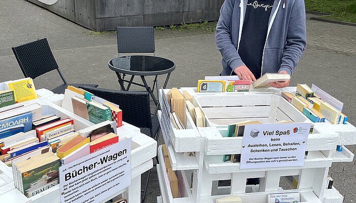 Ein Jugendlicher stöbert im rollenden Bücherwagen.