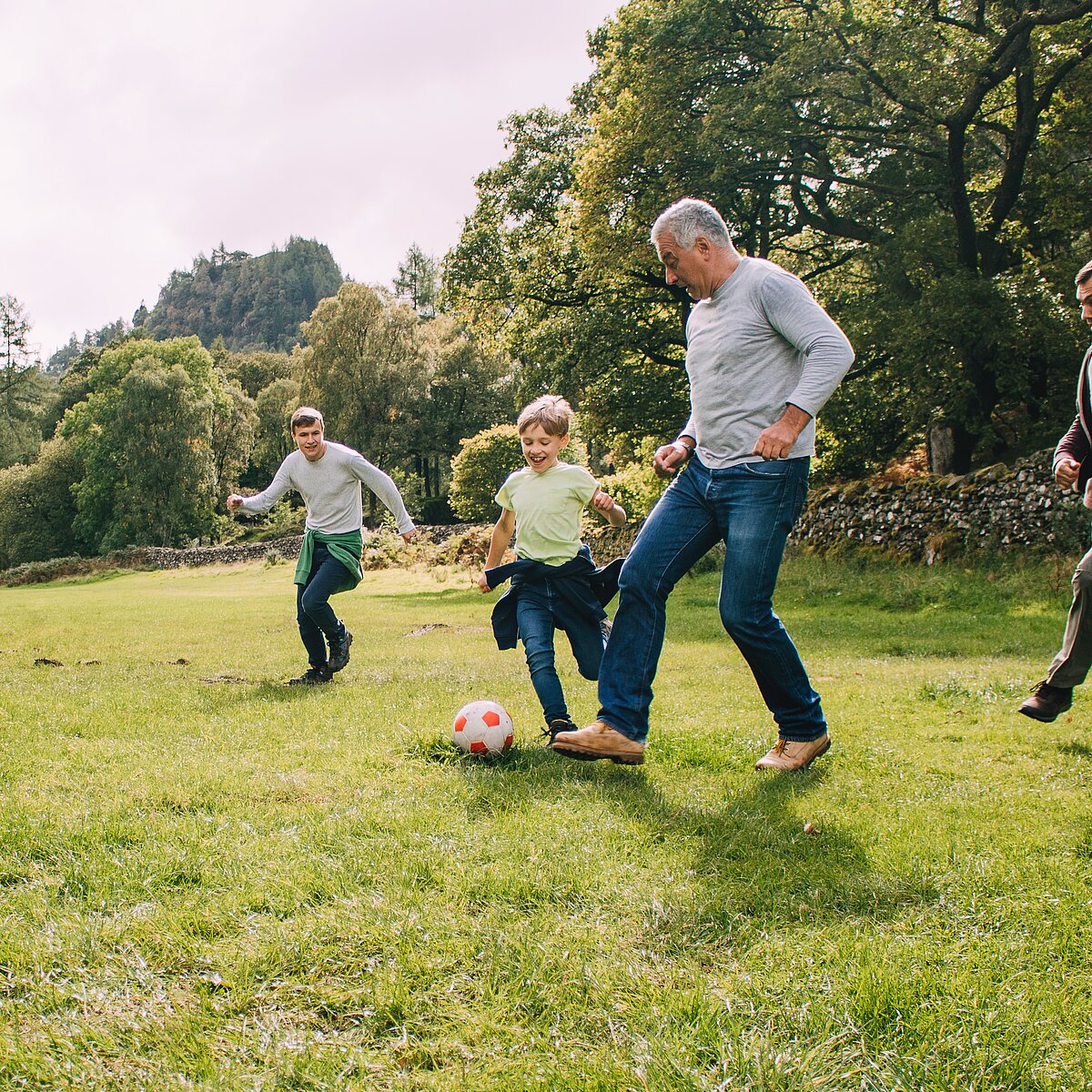 Kinder spielen Fußball mit ihrem Opa.