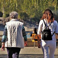 Jüngere und ältere Frau beim Spaziergang im Park