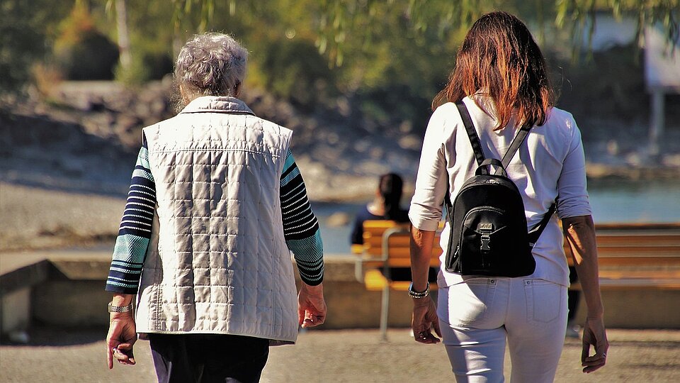 Jüngere und ältere Frau beim Spaziergang im Park