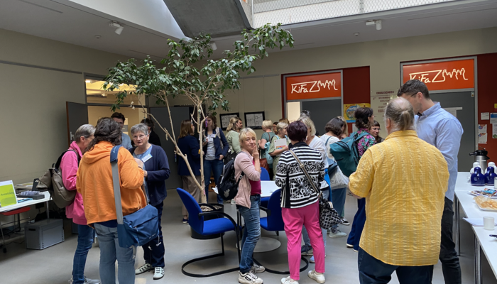 Blick von oben auf viele Menschen, die in einem Foyer stehen und sich in verschiedenen Gruppen unterhalten