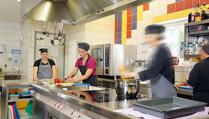 Vier Frauen kochen in einer Großküche