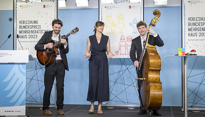 Eine Band aus drei Musiker:innen spielt auf einer Bühne. 