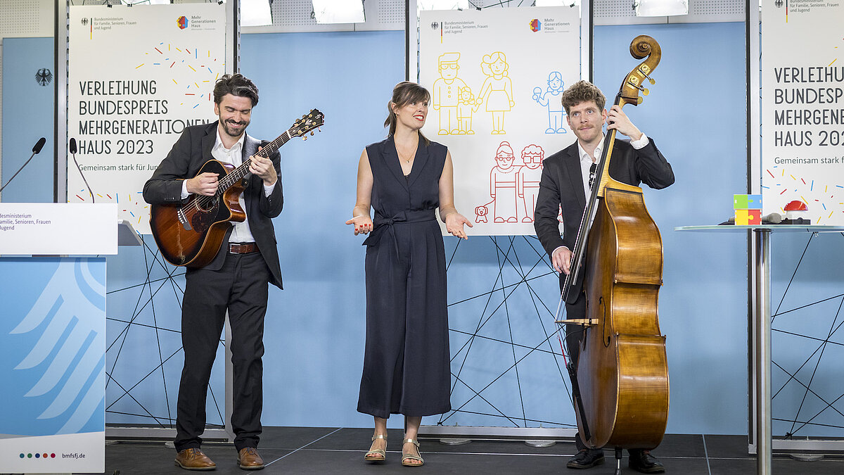 Eine Band aus drei Musiker:innen spielt auf einer Bühne. 