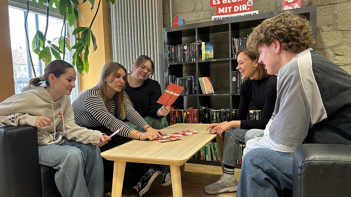 Fünf Jugendliche sitzen an einem Tisch und sprechen miteinander